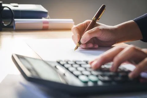 Calculator and Financial data analyzing hand writing and counting in office.. Stock Photos