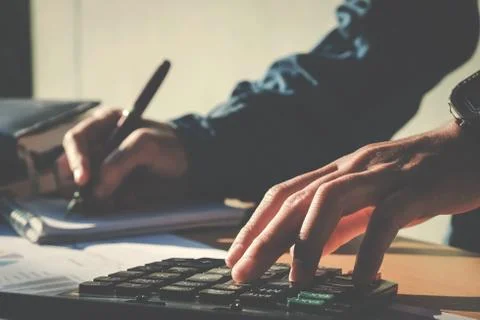 Calculator and Financial data analyzing hand writing and counting in office.. Stock Photos