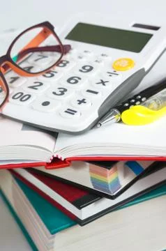 Calculator and pen on book stack with eyeglasses  for financial and accountin Stock Photos