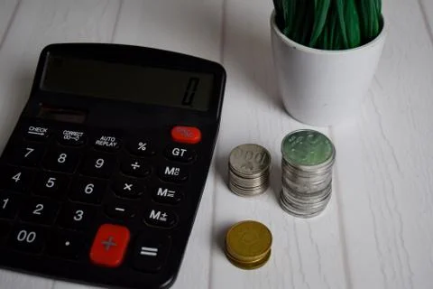 Calculator and the stack of coint isolated on office desk. calculating salary Foto stock