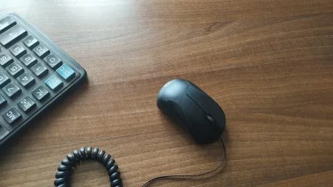 Calculator buttons, wired computer mouse and coiled wire on a wooden table. C Stock Photos