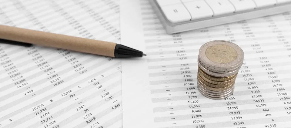 Calculator on financial statement and stack of coins Stock Photos