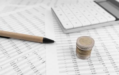 Calculator on financial statement and stack of coins Stock Photos