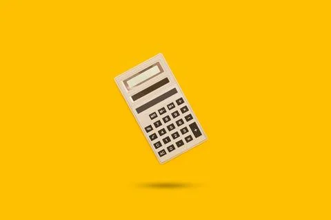 A calculator floating on a yellow background with a copy space Stock Photos