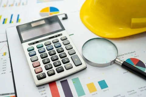 Calculator on graph with construction helmet for working project in office. Stock Photos