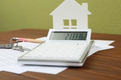 Calculator, house model, keys and documents on wooden table. Real estate agen Stock Photos
