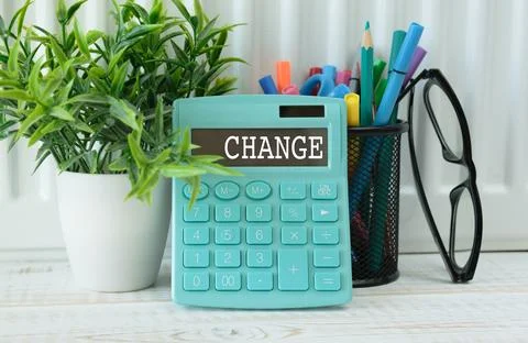 A calculator with the inscription CHANGE is placed in the stack of document.. Foto stock