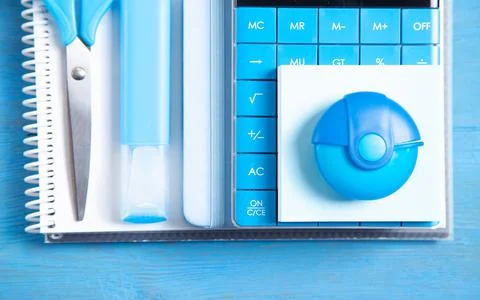 Calculator, note, eraser, scissors, marker on the blue background. Stock Photos
