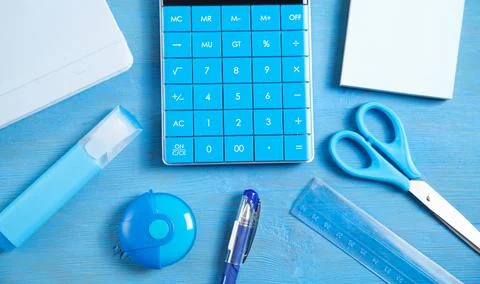 Calculator, note, eraser, scissors, marker on the blue background. Stock Photos