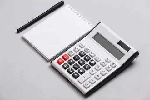 Calculator with notepad and pen on gray surface Stock Photos