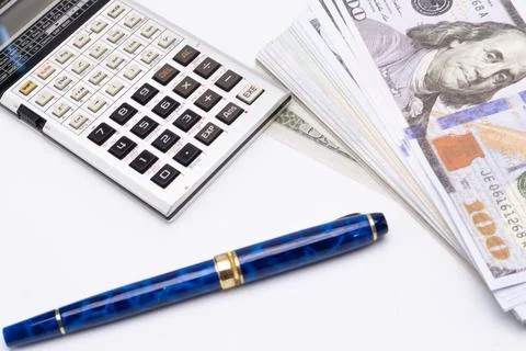 Calculator, Pen, and Stack of Hundred Dollar Bills on White Background, Fin.. Stock Photos