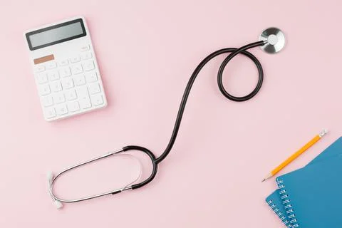Calculator with a stethoscope on a pink table. Stock Photos
