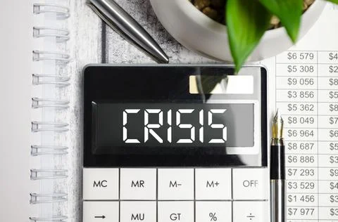 Calculator with the text CRISIS on display on the notebook Stock Photos