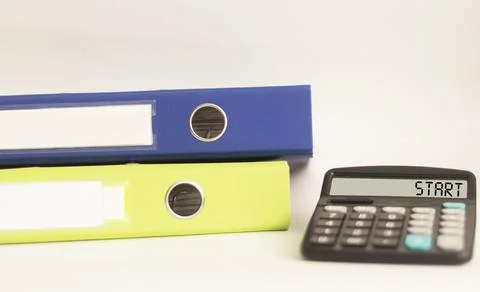 Calculator with text Start. Multi-colored folders with documents lie on a whi Stock Photos
