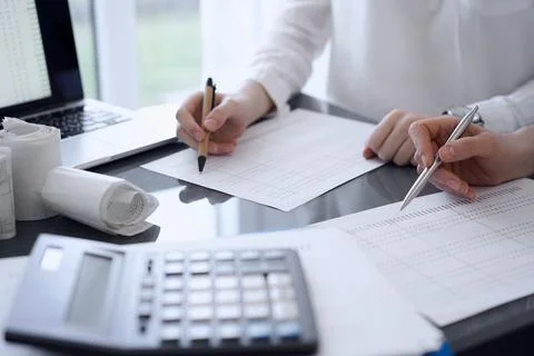 Calculator is waiting to be used while Two accountants are ready to count taxes Stock Photos