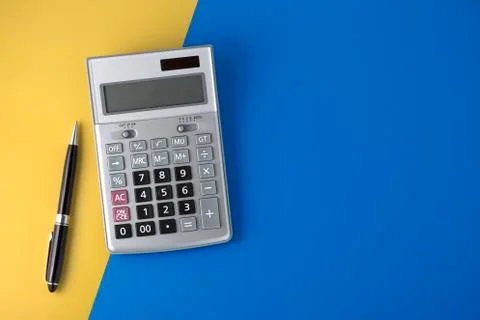 Calculator on yellow and blue background with black pen, flat lay with space Stock Photos