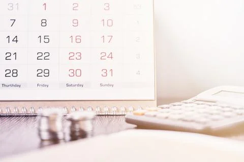 Calendar, calculator and stack of coins in office Stock Photos