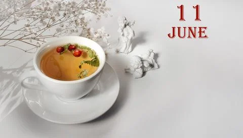 Calendar date on light background with a porcelain cup of green tea, white gy Stock Photos