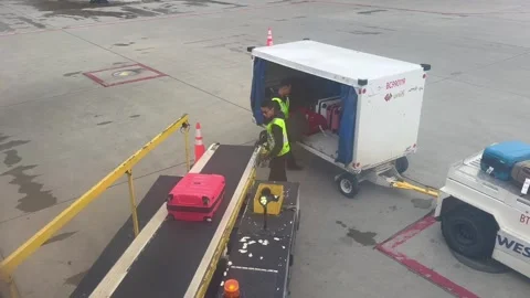 Calgary, Canada - June 11, 2026: Two airport baggage handlers in yellow vests lo Stock Footage 341925769