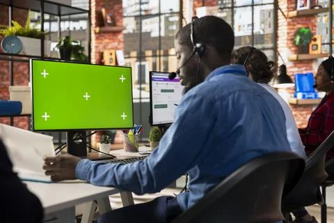 Call center admin at green screen PC desk reading paperwork Stock Photos