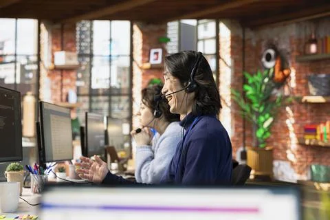 Call center agent laughing while talking with funny customer using headset mic Stock Photos