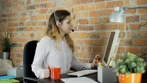 Call center agent talks with client and drinks coffee in the office Stock Footage 70418494