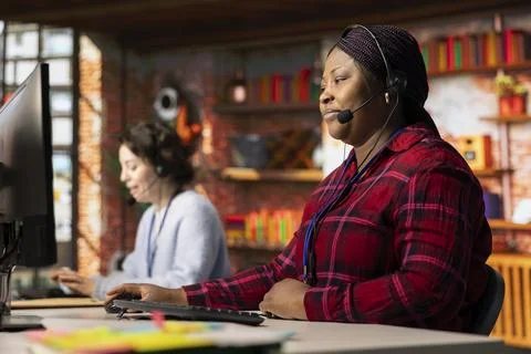 Call center employee using audio headset to answer customers technical inquiries Stock Photos