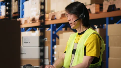 Call center male worker answer help line calls in a logistics warehouse Stock Footage 312836494