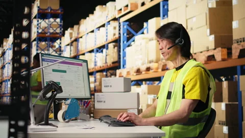 Call center male worker answer help line calls in a logistics warehouse Stock Footage 312837017