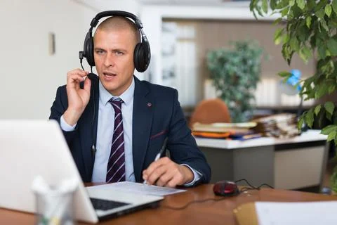Call center man operator with headset talking with client in office Stock Photos