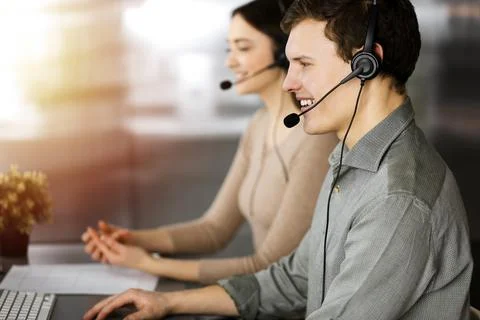 Call center operators at work. Two young people in headsets are talking to the Stockfoto's
