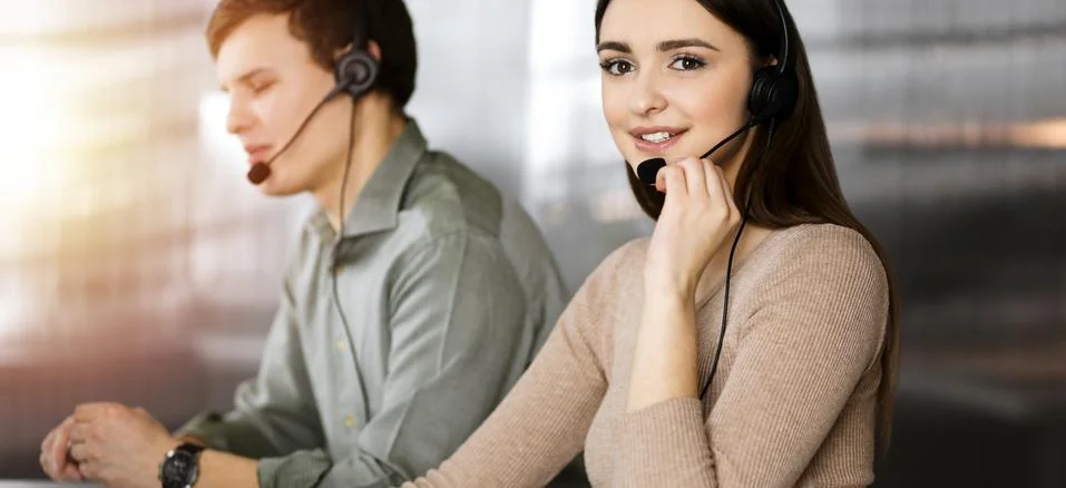 Call center operators at work. Two young people in headsets are talking to the Stockfoto's