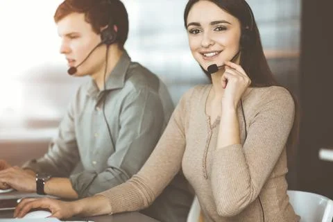 Call center operators at work. Two young people in headsets are talking to the Stockfoto's