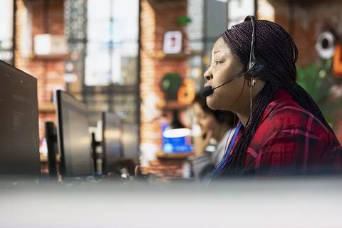 Call center representative in office helping customers by answering questions 写真素材