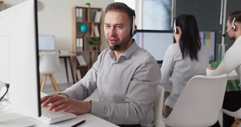 Call center support agents with headsets working in modern office helpdesk team Stock Footage 337619401
