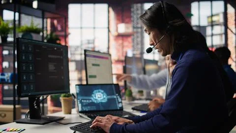 Call center worker arriving at work, using artificial intelligence on laptop 库存照片