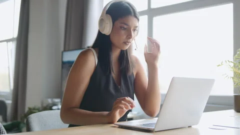 Call center worker assists customers using laptop and headset in an office 스톡 동영상 335764965
