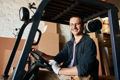 Call me if you need a lift. a young male warehouse worker driving a forklift. Stock Photos