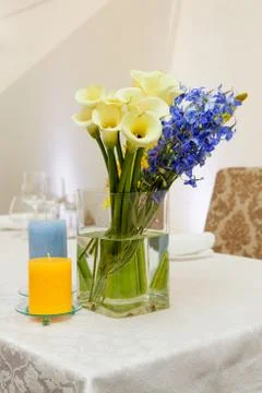 Calla lily and blue flowers in tall glass tube Stock Photos