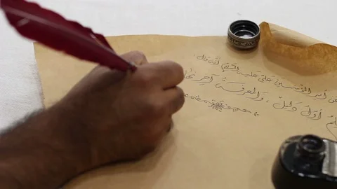Calligrapher writes Arabic words on an old paper Stock Footage 105318691