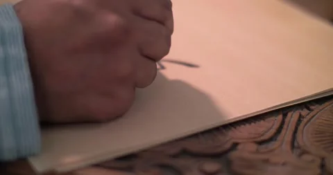 A calligrapher's hand dips a stylo into an inkwell and writes a letter on Stock Footage 257792801