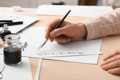 Calligraphy practice with ink and dip pen on white paper, creative writing an Stock Photos