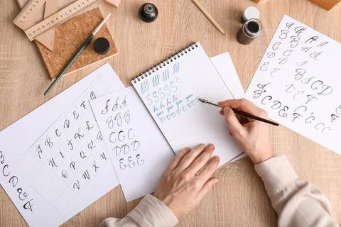 Calligraphy practice session with hand writing alphabet letters and ink pen o Stock Photos