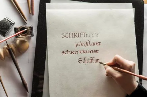 Calligraphy studio hand writes text with ink pen and nib Gothic script on Stock Photos