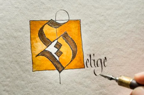 Calligraphy studio hand writes text with pen and nib letter S coated with gold Stock Photos