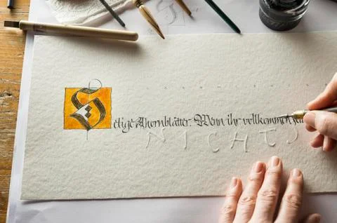 Calligraphy studio hand writes text with pen and nib letter S coated with gold Foto stock