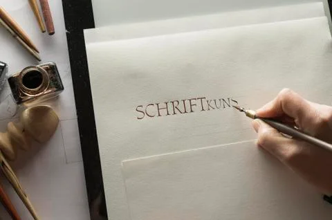 Calligraphy studio hand writes text with ink pen and nib Roman Capitalis Stock Photos