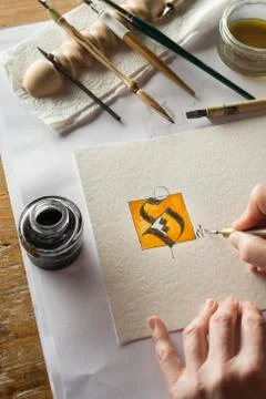 Calligraphy studio hand writing text with pen and nib letter S coated with gold Stock Photos