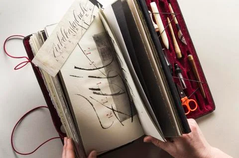 Calligraphy studio hands holding old compass box with calligraphic writings Stock Photos
