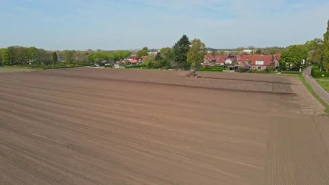 Calm aerial of tractor plowing a empty plot of land at the edge of town Vídeos de archivo 240634954